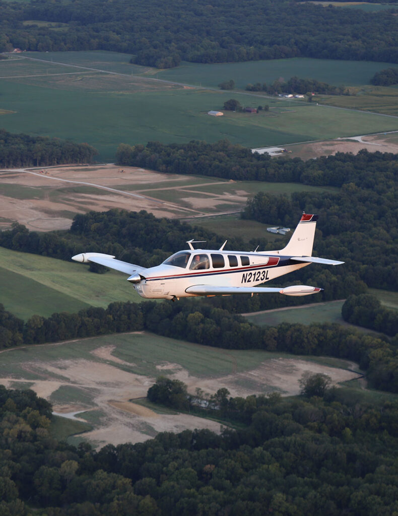 Aerial view of a small black, white, and red airplane flying in the air.